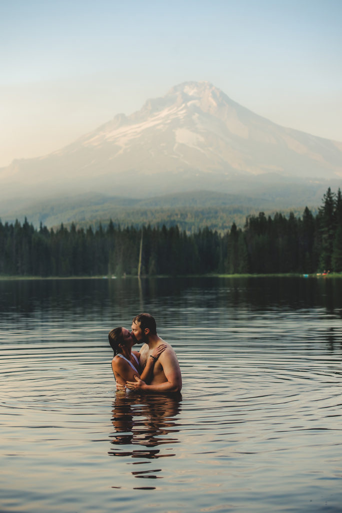 couple kissing in lake with mountain
