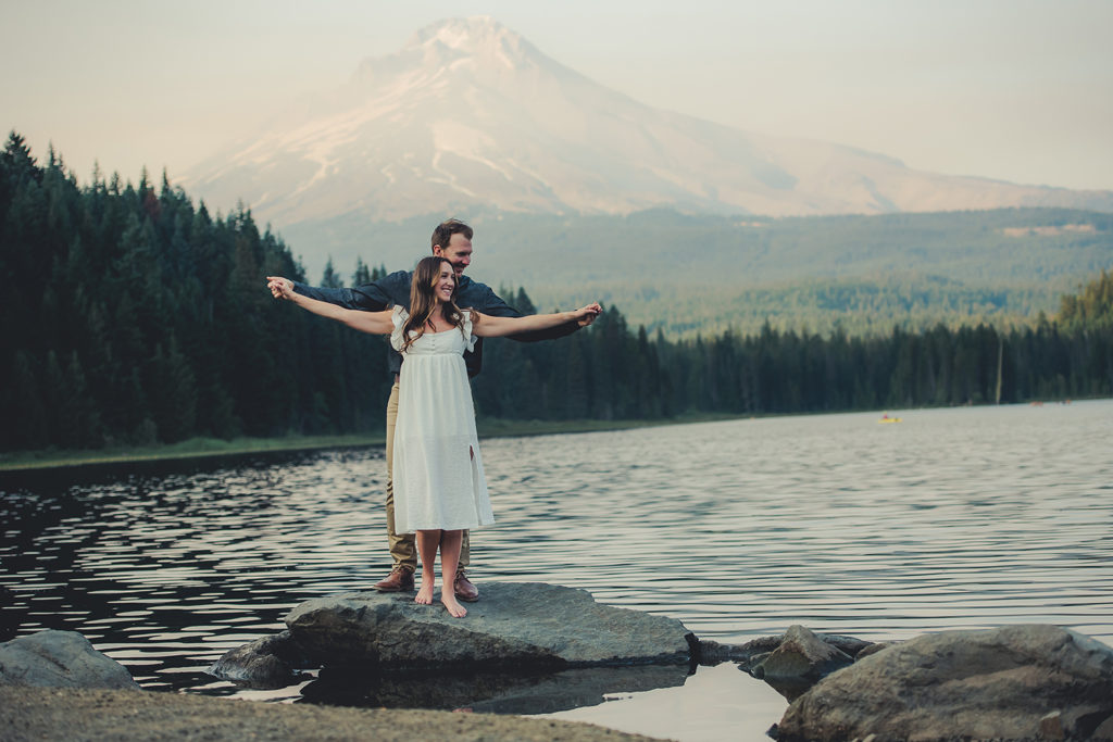 man and woman standing on rock in lake
