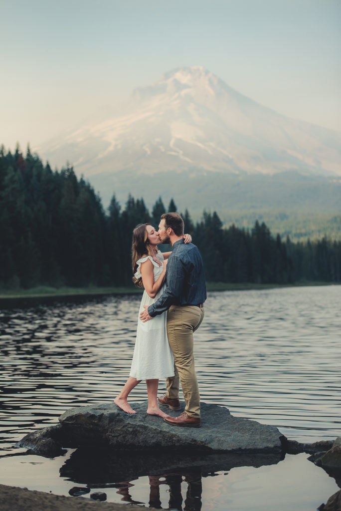 couple kissing in front of mountain.